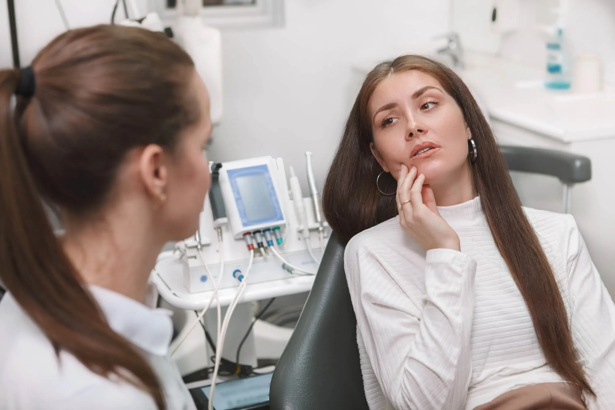 Emergency biological dentist talking to patient in pain