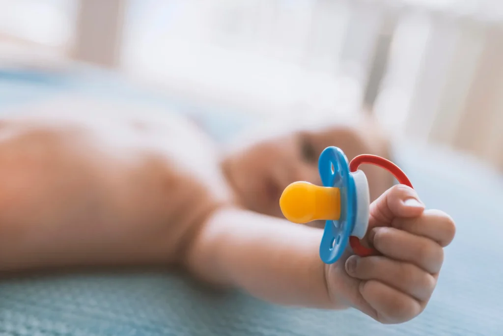 pediatric holistic dentist in Maryland recommends a dental visit for a child holding a pacifier